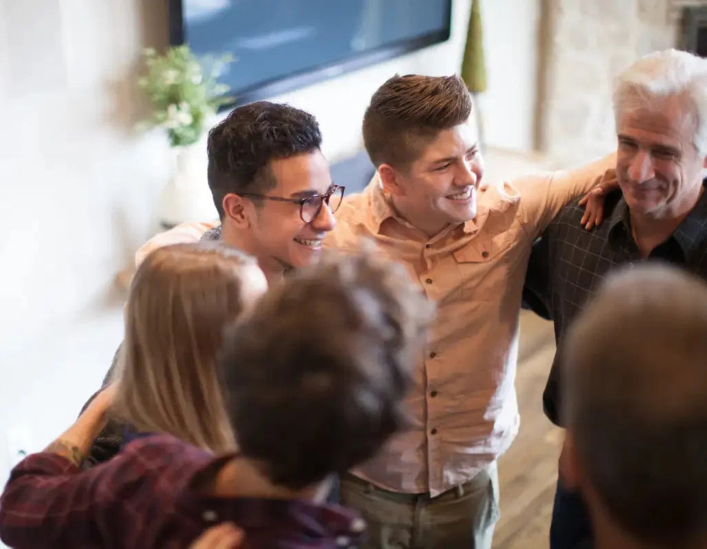 A diverse group of adults standing together in a close circle and connecting in a welcoming community