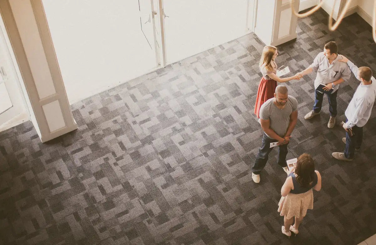 A group of five people gathered in a modern office lobby with patterned carpeting.