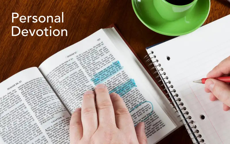 Open bible with highlighted text and a hand resting on the pages.