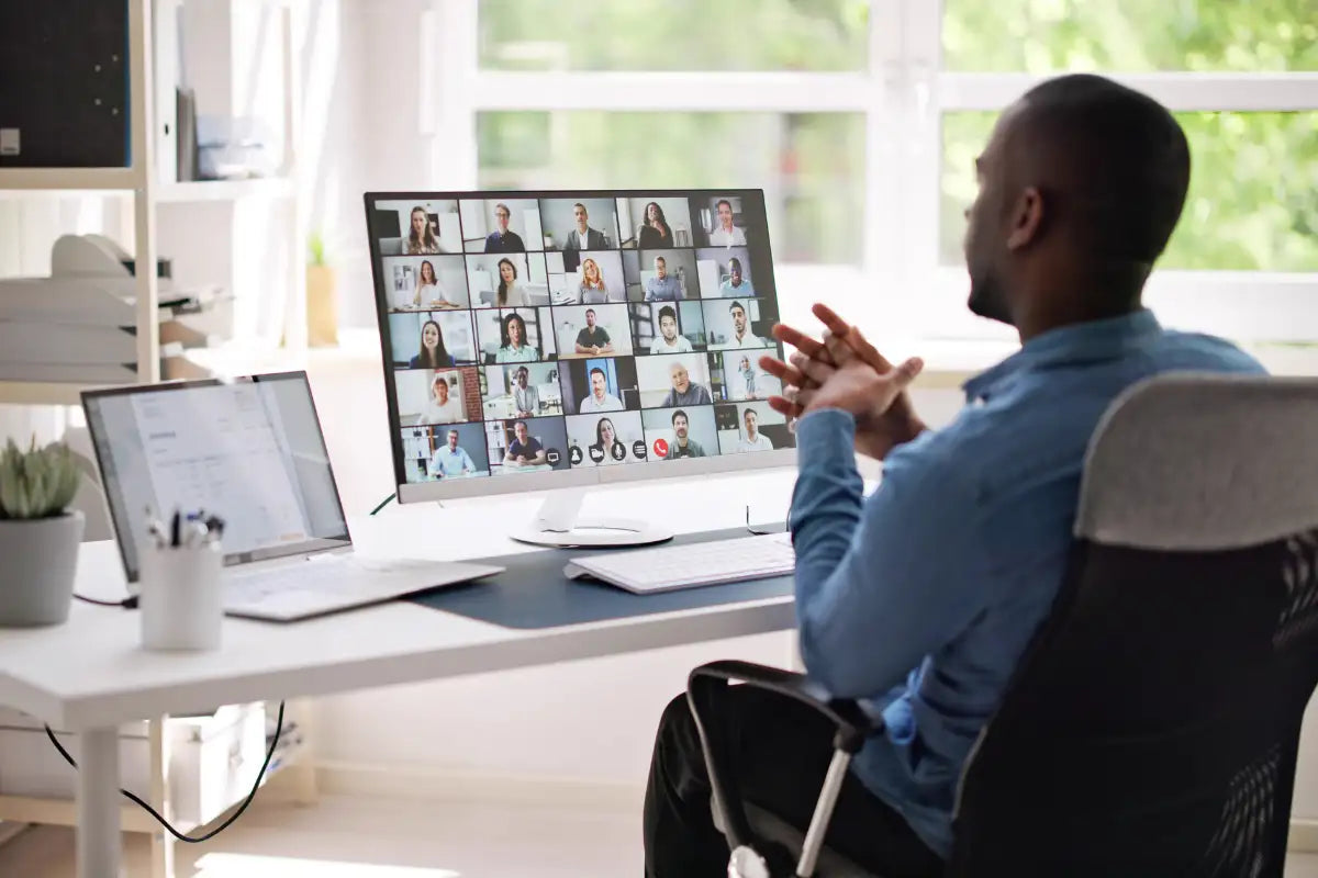 A sleek, modern white monitor displaying a grid of video call participants.