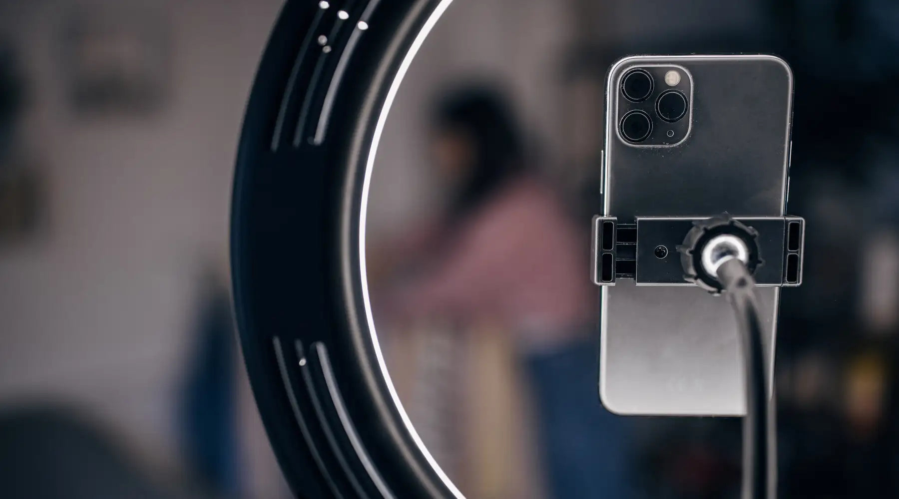 A sleek, silver iphone 12 pro max mounted on a black phone holder with its triple-camera system facing forward.